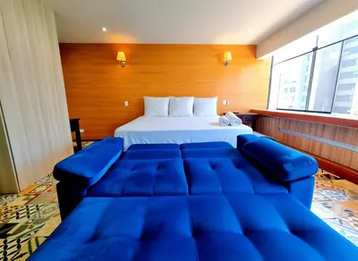 a large bed with a blue couch in a room at San Isidro Suites Basadre 1B403 in Lima