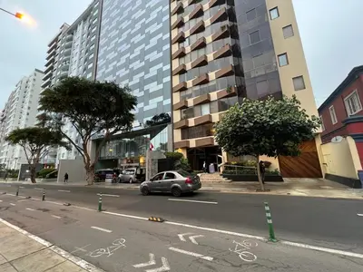 a car driving down a city street with a tall building at APARTAMENTO COMPLETO EN LA MEJOR ZONA DE MIRAFLORES in Lima