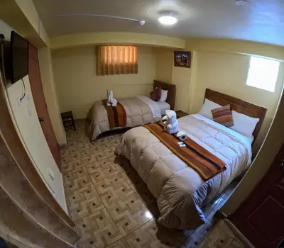 a hotel room with two beds and a television at LA JOYA DE SAN BLAS in Cusco
