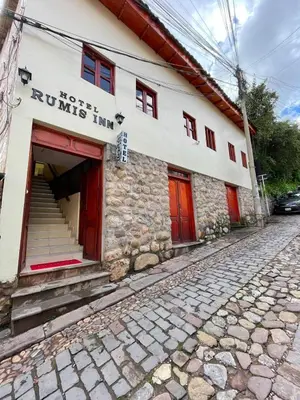 a building with red doors on a cobblestone street at LA JOYA DE SAN BLAS in Cusco