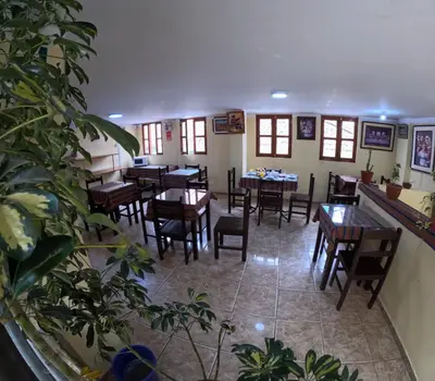 a restaurant with wooden tables and chairs and plants at LA JOYA DE SAN BLAS in Cusco