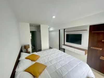 a bedroom with a white bed with two yellow pillows at Departamento amoblado in Lima
