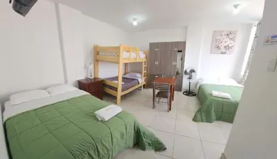 a bedroom with two beds and a table and a chair at Hospedaje Las Parraz in Ica