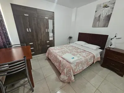 a bedroom with a bed and a table and a desk at Hospedaje Las Parraz in Ica