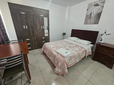 a bedroom with a bed and a table and a desk at Hospedaje Las Parraz in Ica