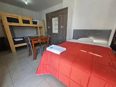 a bedroom with a bed and a desk and a bunk bed at Hospedaje Las Parraz in Ica