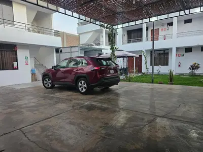 a red car parked in front of a building at Hospedaje Las Parraz in Ica