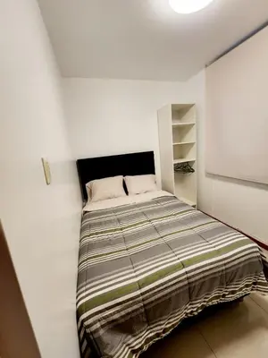 a small bedroom with a bed in a white wall at Departamento familiar en Huacachina in Ica