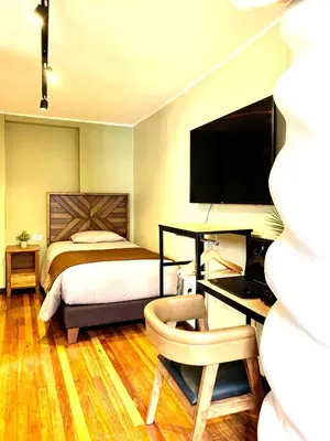a bedroom with a bed and a desk with a computer at Apartamentos Montes in Cusco