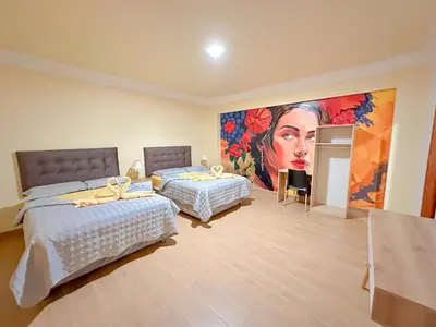 a bedroom with two beds and a painting of a woman at Hotel Retamayo in Ica