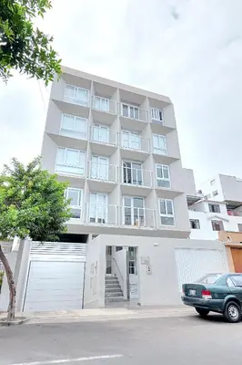 a large white building with a white garage at Quark Apartments in Lima