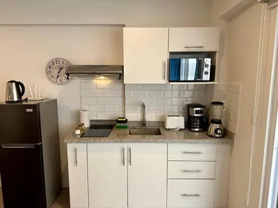 a kitchen with white cabinets and a black refrigerator at Quark Apartments in Lima