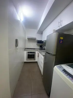 a small kitchen with a refrigerator and white cabinets at Apartamento Temporal en Miraflores in Lima