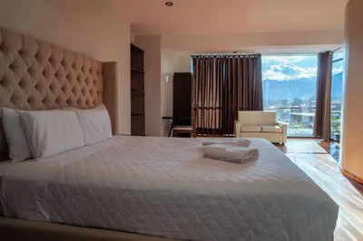 a bedroom with a large bed with a large window at Hotel California Urubamba in Urubamba