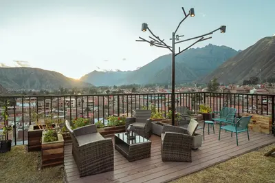a deck with chairs and tables and a view of a city at Hotel California Urubamba in Urubamba