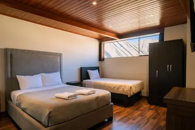 a bedroom with two beds and a window at Hotel California Urubamba in Urubamba