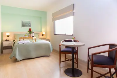a bedroom with a bed and a table and chairs at Hotel San Blas in Lima