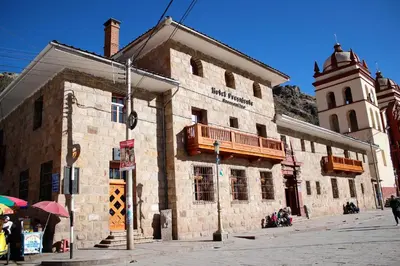 a large stone building with a balcony and a clock tower at Hotel Presidente Huancavelica - Asociado Casa Andina in Huancavelica