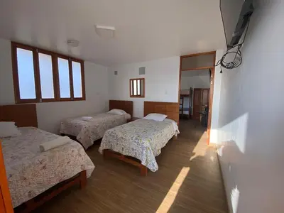 a room with three beds and a hallway with windows at HOTEL HACIENDA SUBTANJALLA CASABLANCA in Ica