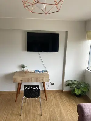 a room with a table and a tv on a wall at Excelente ubicación San Isidro Suite 10 in Lima