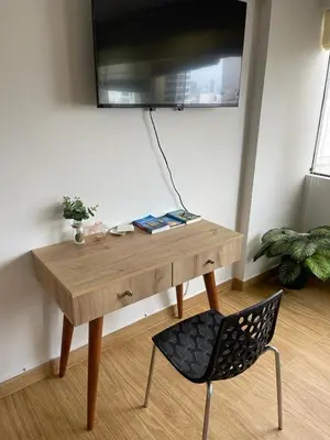 a desk with a chair and a television on a wall at Excelente ubicación San Isidro Suite 10 in Lima