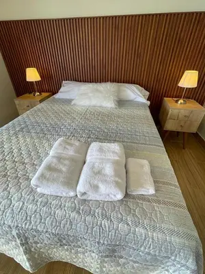 a bed with two pillows and two tables with lamps at Excelente ubicación San Isidro Suite 10 in Lima
