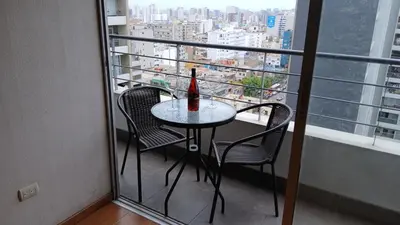 a table with two chairs and a bottle on a balcony at Apartment near to MIRAFLORES, BEACHES & REBAGLIATI HOSPITAL ! Panoramic View,Pool, Gym,Private Park in LINCE in Lima