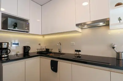 a kitchen with white cabinets and black counter tops at Caster by Wynwood House in Lima