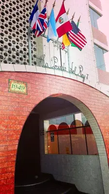 a brick building with flags on top of it at La Posada del Rey - Lima Airport Hostel in Lima