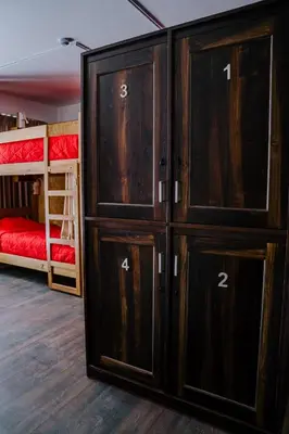 a room with two bunk beds and wooden cabinets at Magar Hostel Bar in Cusco