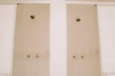 a white shower with three glass doors with buttons at Magar Hostel Bar in Cusco