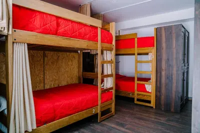 a room with four bunk beds with red sheets at Magar Hostel Bar in Cusco