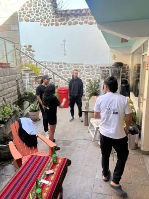 a group of people standing around a bench with bottles on it at Magar Hostel Bar in Cusco