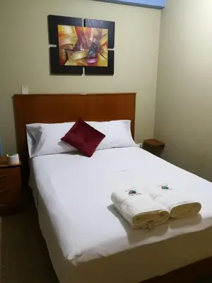 a bedroom with a white bed with two towels on it at Hostal Aventura Total Perú_lunahuana in Lunahuaná