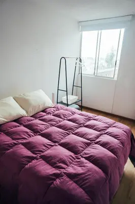a purple bed in a room with a window at Acogedor departamento con amplia terraza in Lima