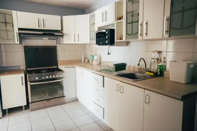 a kitchen with white cabinets and a sink at Acogedor departamento con amplia terraza in Lima