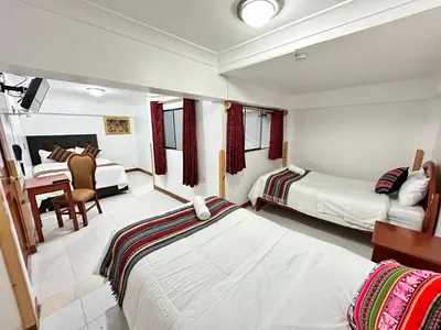 a hotel room with two beds and a table and chairs at Libertrek Centro Inn in Cusco
