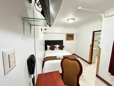 a bedroom with a bed and a desk and a table at Libertrek Centro Inn in Cusco