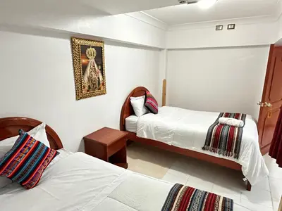 a bedroom with two beds and a picture on the wall at Libertrek Centro Inn in Cusco