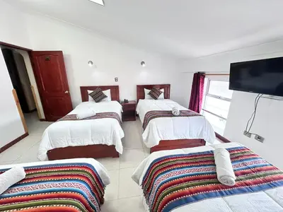 a room with four beds and a flat screen tv at Libertrek Centro Inn in Cusco