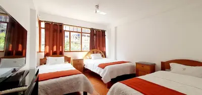 a room with two beds and two windows at Hotel Romero Machupicchu in Machu Picchu