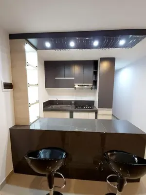 a kitchen with two black chairs and a counter at Acogedor departamento en Huacachina in Ica