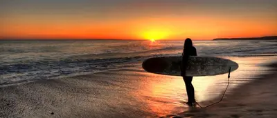 a woman standing on the beach holding a surfboard at Posada del Mirador Italyan Villa in San Bartolo