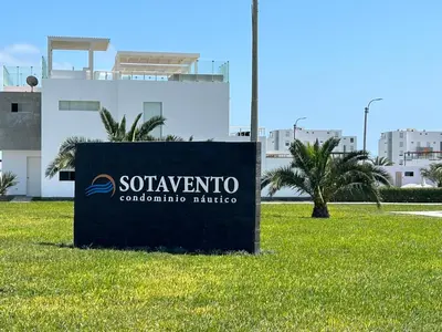 a sign in the grass in front of a building at Departamento Paracas vista al mar in Paracas