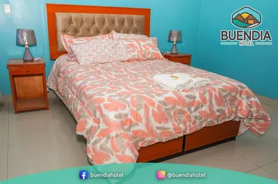 a bedroom with a bed with two night stands and two lamps at BUENDIA HOTEL in Pueblo Viejo