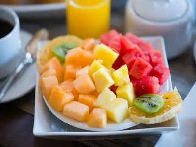 a plate of fruit on a table with a cup of coffee at Atiq Boutique Hotel in Cusco