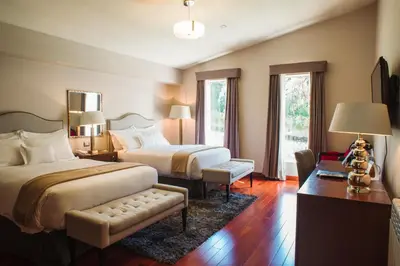 a hotel room with two beds and a table and chairs at Atiq Boutique Hotel in Cusco