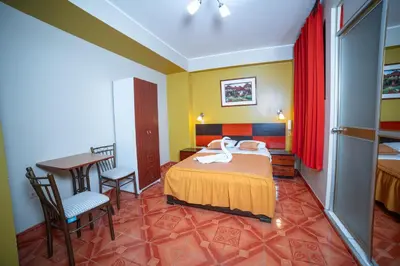 a bedroom with a bed and a desk and a table at Hotel Mayros in Satipo