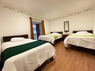 a bedroom with two beds with white and green sheets at Casa Justina in Cusco