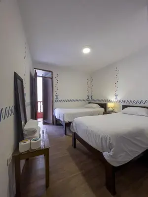 a hotel room with two beds and a tv at Casa Justina in Cusco